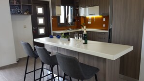 Ett modernt kök med en central köksö, barstolar och en vinflaska.