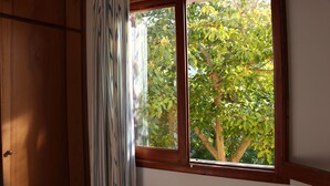 A window with a view of a tree and a wooden door. - Vacation home close to the beach with private pool. Quiet location. 5min to Sa Coma beach. (Sa Coma)