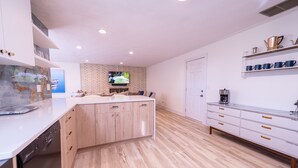 A modern kitchen with white cabinetry, a central island, and a brick accent wall. - .6 Walk to Carmel Midtown. Quiet and secure neighborhood. Plus massage chair! (Carmel)