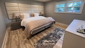 A bedroom with a bed, bedside tables, a nightstand, a window, and a small table with a bottle. - .6 Walk to Carmel Midtown. Quiet and secure neighborhood. Plus massage chair! (Carmel)