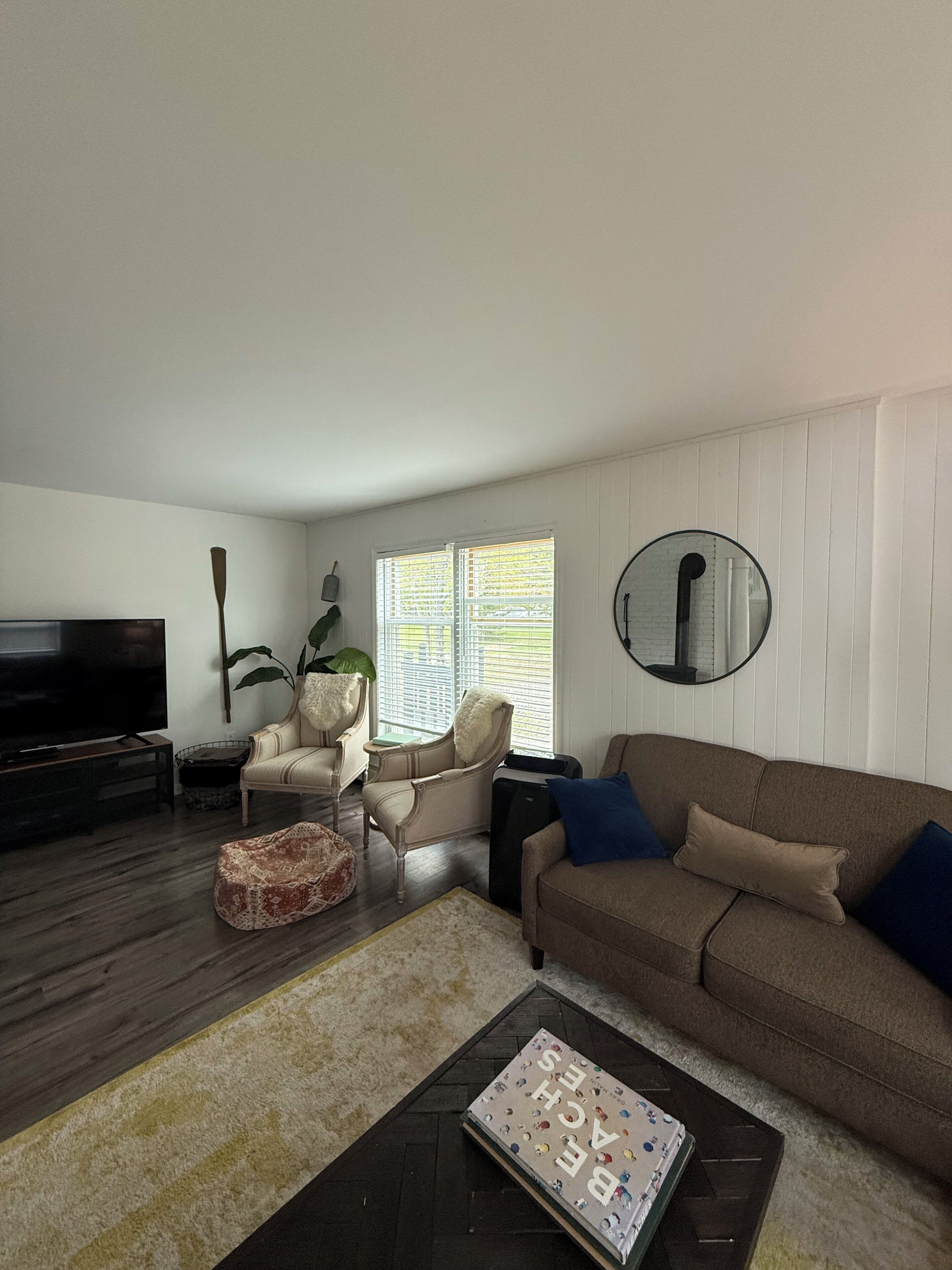 A living room with a sofa, armchair, coffee table, and a TV.