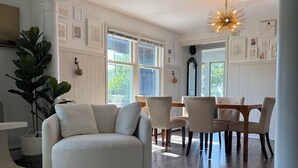 Una sala de estar con un sofá, una mesa de comedor, sillas, una araña y obras de arte en las paredes.