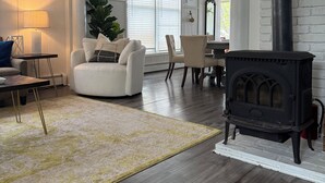Una sala de estar con chimenea, sofá, mesa de centro y alfombra.