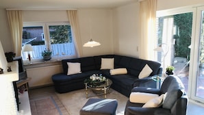 Un salon moderne avec un canapé d’angle, une table basse en verre et une petite table d’appoint.