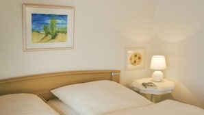 Une chambre d’hôtel avec deux lits, une table de chevet avec une lampe et un tableau encadré au mur.