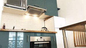 A compact kitchen with a microwave, oven, and a wooden countertop. - romantic paris in the heart of paris (Paris)