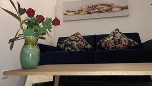 A living room with a dark blue sofa, a green vase with red roses, and a framed picture on the wall. - romantic paris in the heart of paris (Paris)