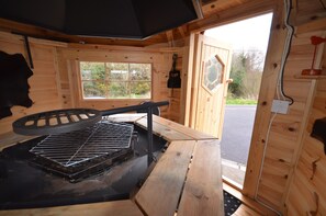 Ein Holzblockhaus-Interieur mit einem Grill, einem Fenster und einer Tür, die nach draußen führt.