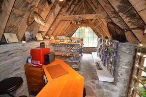 Ein Dachzimmer mit Holzbalkendecke, Steinwänden, einem Holztisch und einer Sammlung von Angelausrüstung.