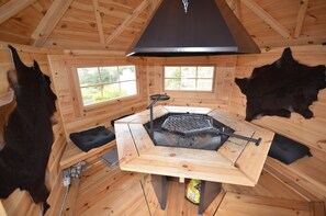 Eine Holzhütte mit Grillplatz, zwei Fenstern und Lederverkleidungen an den Wänden.