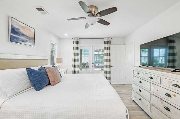 A bedroom with a bed, a ceiling fan, a dresser, and a TV. - Gulf view, Steps to beach, heated pool, walk to restaurants (Destin)