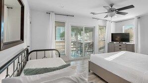 A bedroom with a bed, a TV, a ceiling fan, and a view of the outside. - Gulf view, Steps to beach, heated pool, walk to restaurants (Destin)
