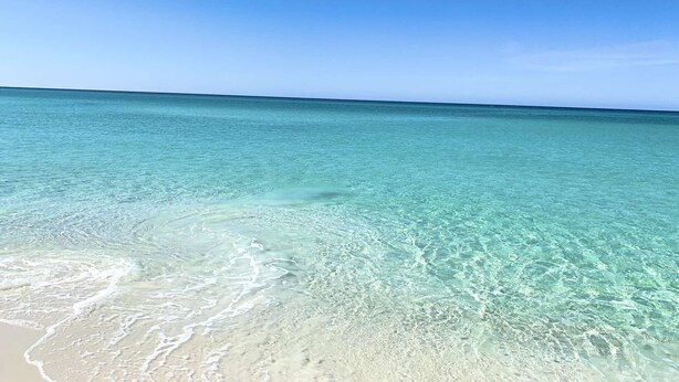 A clear view of a beach with shallow, turquoise waters and a sandy shoreline. - Gulf view, Steps to beach, heated pool, walk to restaurants (Destin)