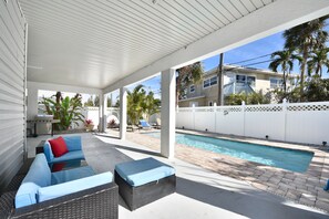 Un espacio exterior techado con piscina, sillas de descanso y zona de comedor.