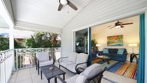 Un patio couvert avec un ventilateur de plafond, une table à manger et deux chaises.
