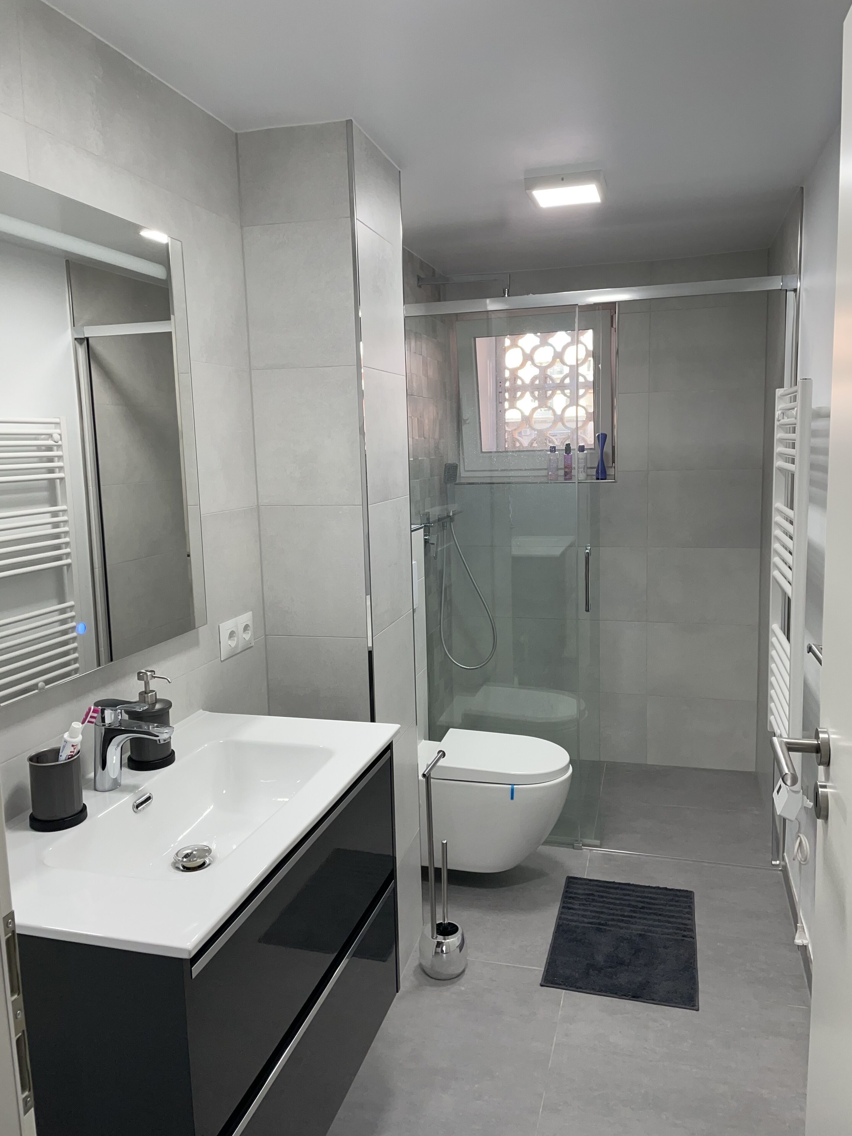 Un bany modern amb dutxa envidriada, un lavabo blanc i un vàter.
