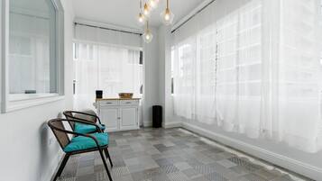 A spacious room with a patterned floor, white walls, and a large window with sheer curtains.