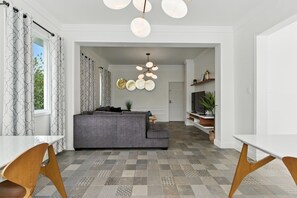 Ein modernes Wohnzimmer mit grauem Sofa, einem gemusterten Boden und einem einzigartigen Kronleuchter.