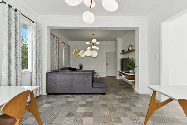 A modern living room with a grey sofa, patterned floor, and a unique chandelier.
