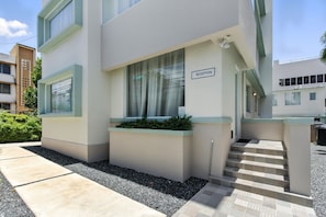 A modern building with a reception area, steps leading to an entrance, and a small garden area.