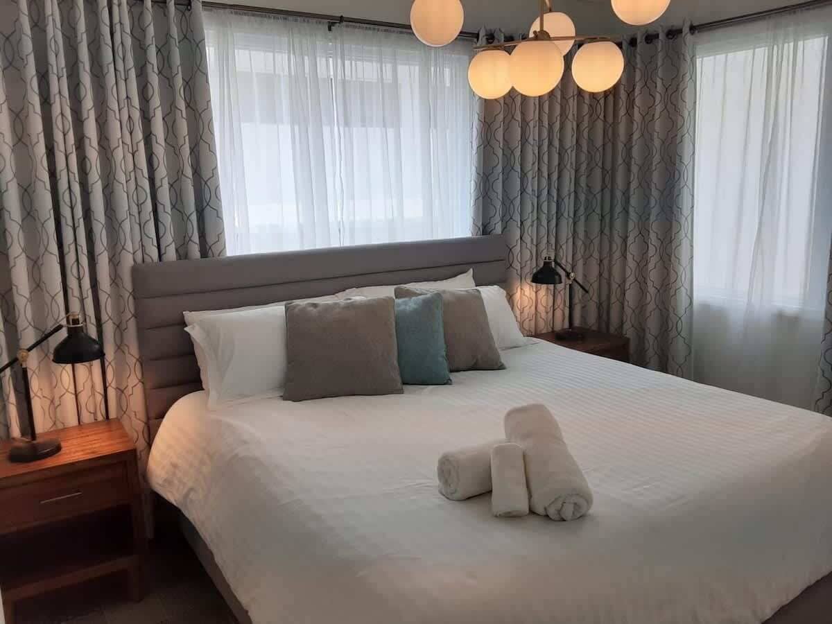 Ein Hotelzimmer mit einem großen Bett, zwei Nachttischen, einer Lampe und einem Satz Handtücher.