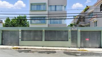 A building with a closed metal gate, a sign indicating 'No Estacionamiento' (No Parking), and a sign with 'Villa 154' and a website URL.