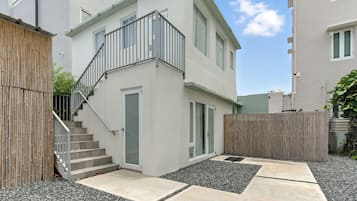 Ein modernes, zweistöckiges Gebäude mit einer Treppe zu einer Tür, einem Balkon und einem Holzzaun.