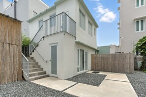A modern two-story building with a staircase leading to a door, a balcony, and a wooden fence.