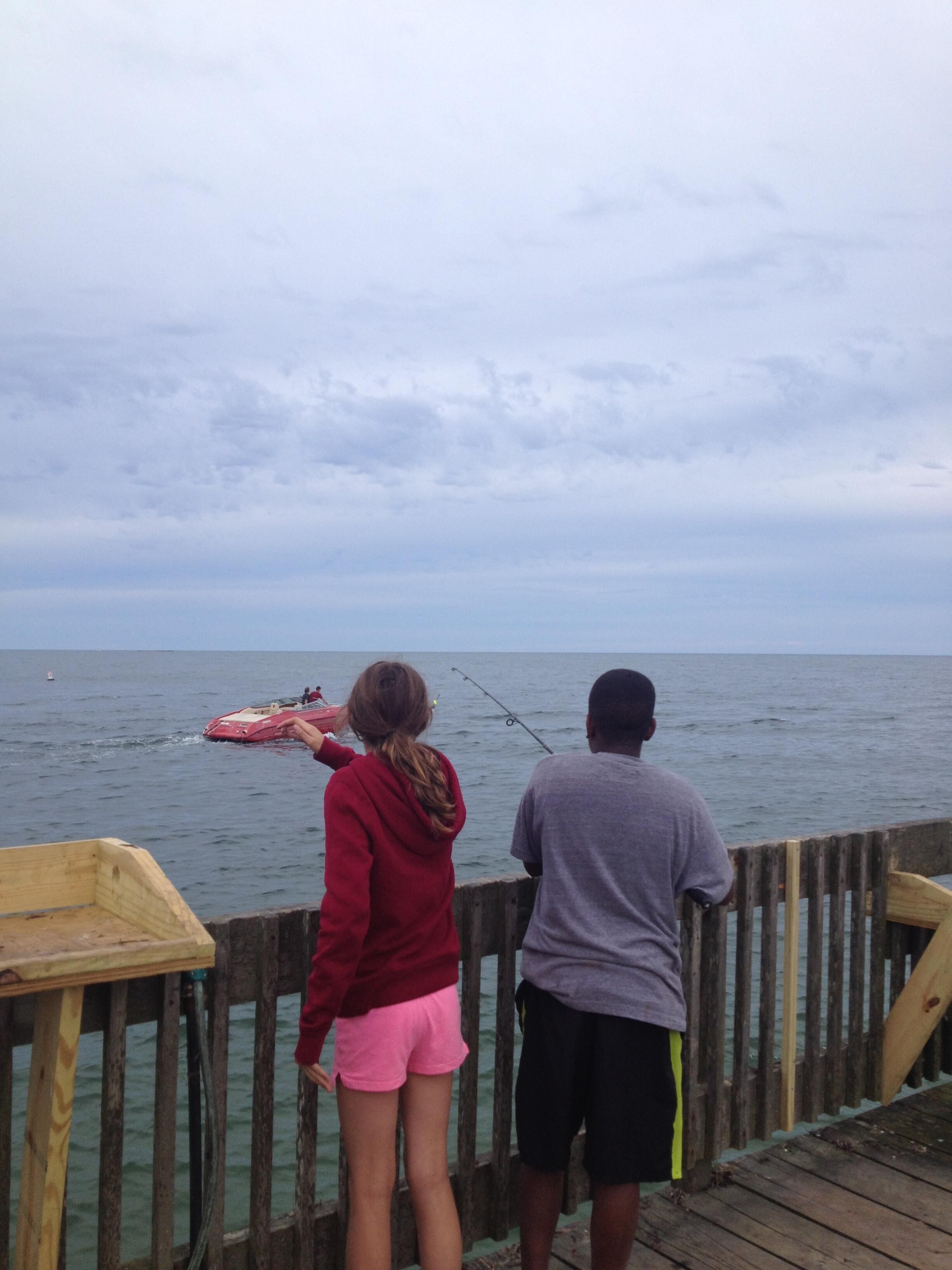 A wooden pier extending into a body of water with a cloudy sky above.