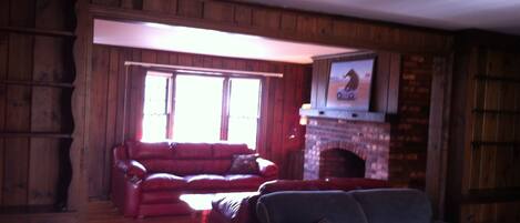 A living room with a fireplace, a red sofa, and a blue sofa.
