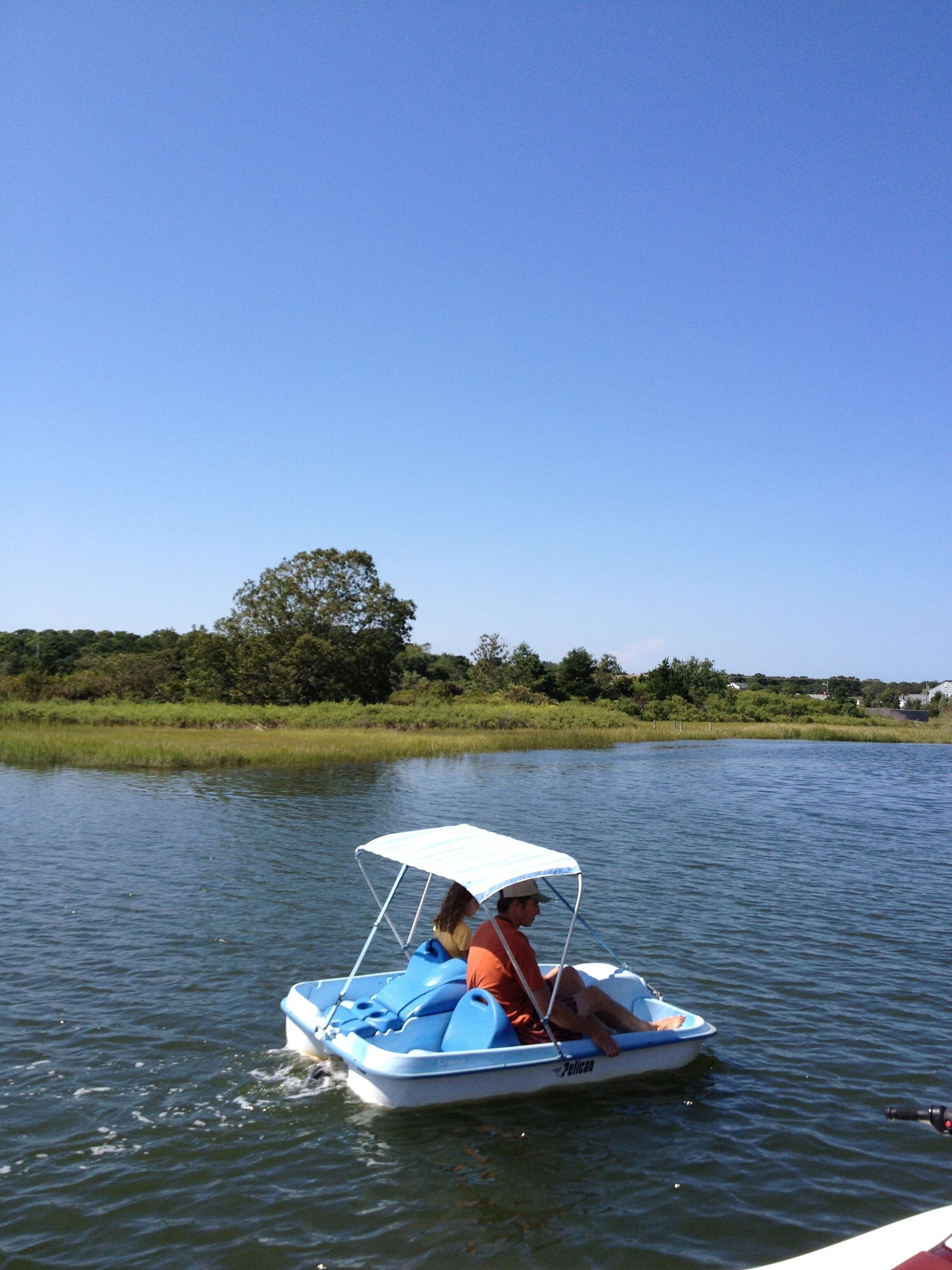 A small boat with a canopy, two people, and calm water.