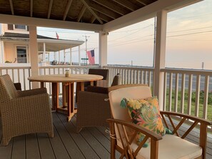 A covered outdoor area with wicker furniture, a wooden table, and a view of the waterfront. - Ocean Front With Panoramic Views - Walk to the Beach and Town! (Marshfield)