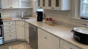 Una cocina moderna con armarios blancos, encimera de granito, cafetera y olla de cocción lenta.