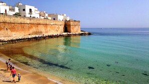 A coastal scene with a clear beach, a stone wall, and white buildings. - House with character (Monopoli)