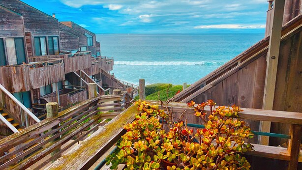 Un escalier en bois menant à un balcon d’où l’on a une vue sur l’océan.