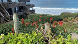 Un bâtiment situé sur la côte, avec une façade en bois, un balcon et une vue sur l’océan.