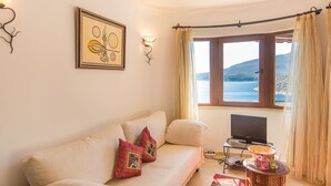 Ein Wohnzimmer mit einer Couch, einem Fernseher und einem Fenster mit Vorhängen.