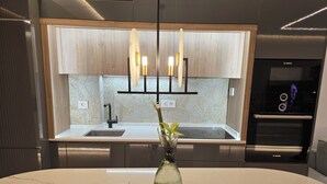 A modern kitchen with a white marble countertop, a built-in sink, and a Bosch oven.