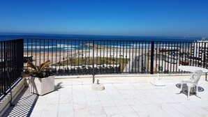 A balcony with a view of the beach and ocean.