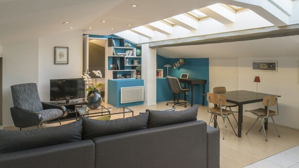 Un salon moderne comprenant un canapé, un téléviseur et un coin repas avec des chaises et une table.