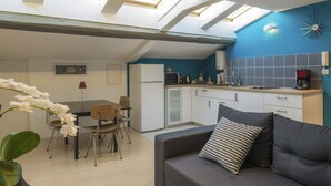Une cuisine compacte avec un coin repas, un canapé agrémenté d’un coussin à motifs et une lucarne au-dessus.