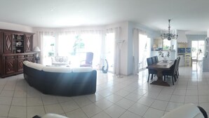 A spacious living room with a large sectional sofa, a dining area with a table and chairs, a kitchen in the background, and a fireplace. - BETWEEN ARCACHON AND OCEAN, BIG HOUSE - LE TEMPLE (Le Temple)