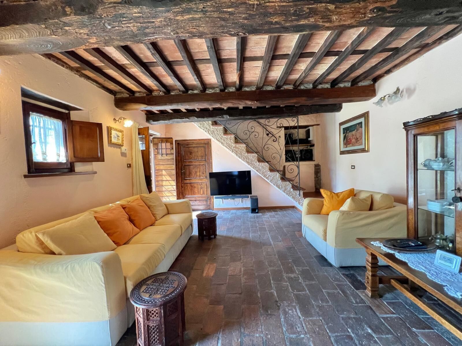 A living room with two sofas, a small round table, and a staircase leading to an upper level.