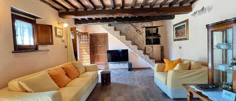 A living room with two sofas, a small round table, and a staircase leading to an upper level.