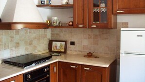 A kitchen with wooden cabinets, a stove, and a refrigerator. - Roccascalegna, Chieti (Roccascalegna)