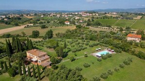 Vista aérea de una propiedad en el campo con una casa grande, una piscina y viñedos circundantes.