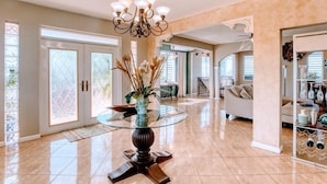 A spacious living area with a glass-top coffee table, a chandelier, and a view of the outdoors through large sliding doors. - Mountaintop Villa with Spectacular Sunset View of Caribbean  (rincon)