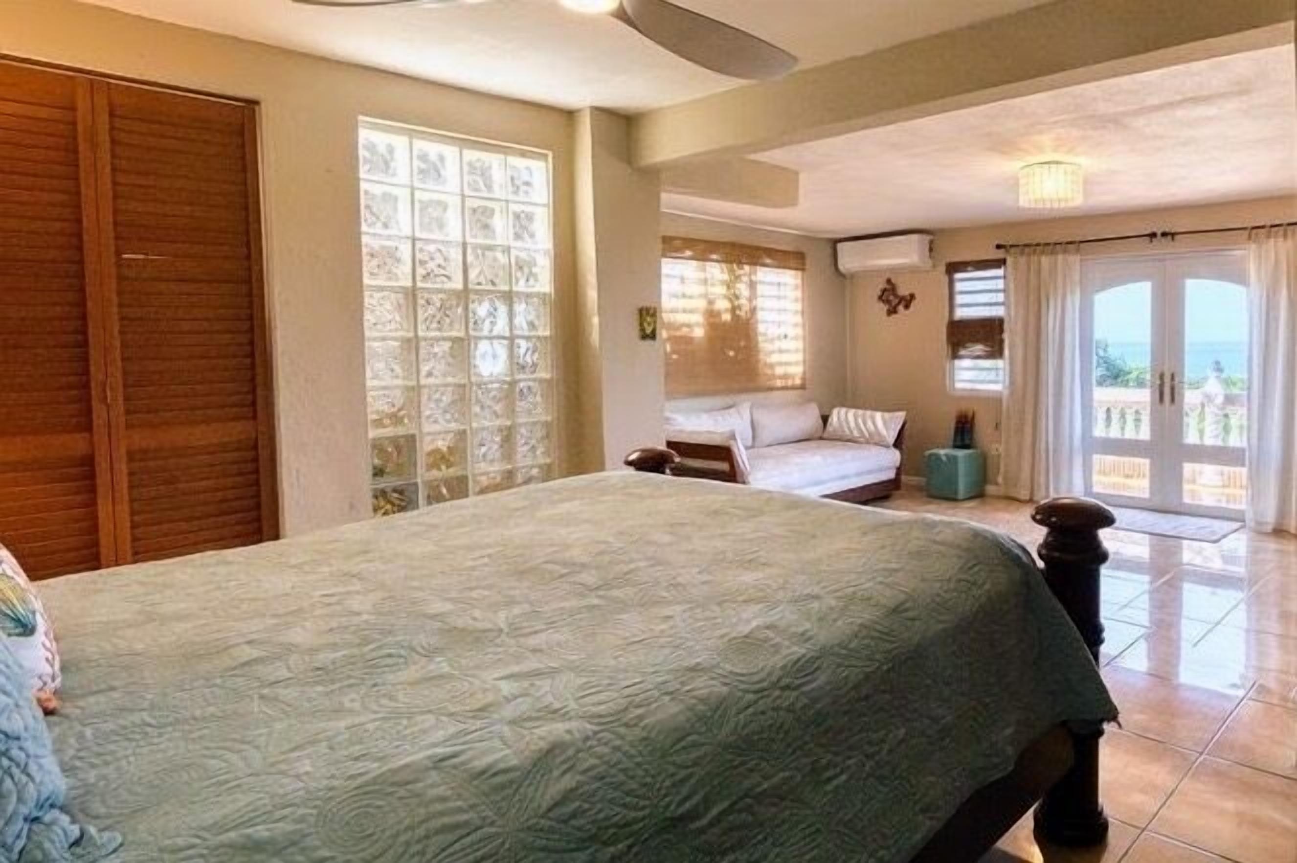 Une chambre à coucher comprenant un lit, une armoire, une fenêtre ornée de vitraux et donnant sur l’extérieur.
