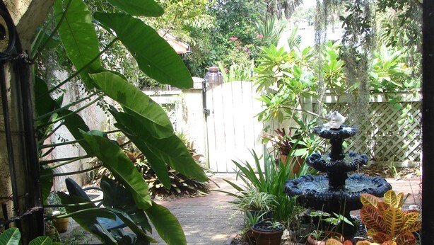 A garden with a fountain, potted plants, and a stone archway.