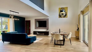 Una sala de estar moderna con un sofá azul, una mesa de comedor con sillas, un televisor de pantalla plana y una chimenea.